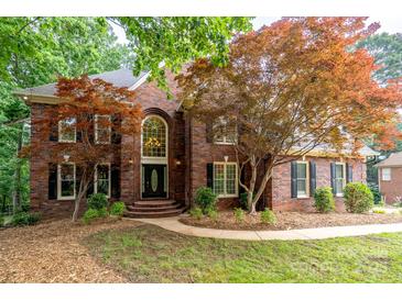 Charming brick home featuring mature trees, manicured lawn, and a welcoming front entrance at 4672 Snow Dr, Harrisburg, NC 28075