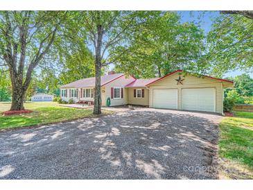 Charming single-story home with a red metal roof, an attached two-car garage, and a spacious front yard at 8255 Castor Rd, Salisbury, NC 28146