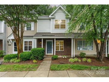 Charming townhome with a brick facade, manicured landscaping, and a welcoming covered front porch at 10223 Reindeer Way Ln, Charlotte, NC 28216