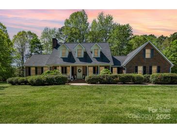 Charming brick home with a welcoming front porch, manicured lawn and mature landscaping at 127 Fantasy Ln, Mooresville, NC 28117