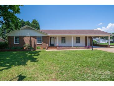 Charming brick home featuring a well-manicured lawn, covered porch, and convenient carport at 1613 Spangler Dr, Shelby, NC 28150