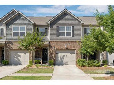 Charming townhome showcasing a brick and shake facade, complemented by a one-car garage and professionally landscaped front yard at 344 Kennebel Pl, Fort Mill, SC 29715