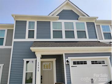 Charming two-story townhome with blue siding, white trim, and an attached one car garage at 1598 Respect St, Concord, NC 28027