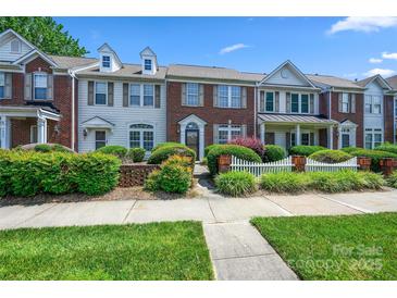 Charming townhome with brick and siding exterior, manicured landscaping, and a picket fence under a clear, blue sky at 7007 Creft Cir, Indian Trail, NC 28079
