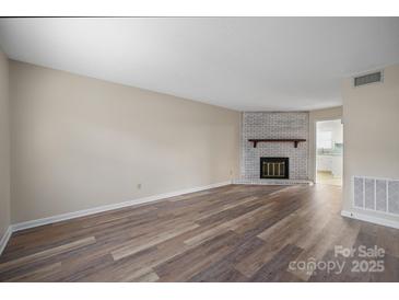 Bright living room featuring a brick fireplace and hardwood floors; open floor plan at 1330 5Th Ne St, Hickory, NC 28601