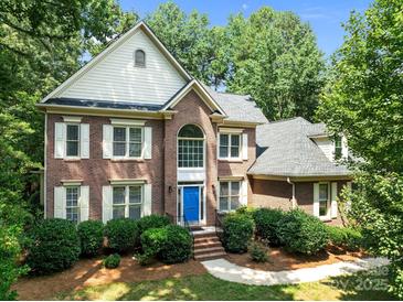Charming two-story brick home with a blue front door, lush landscaping, and a classic architectural design at 15400 Groveland St, Huntersville, NC 28078