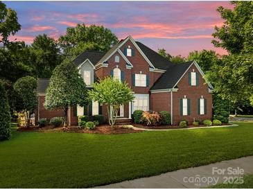 Beautiful two-story brick home with a well-manicured lawn and colorful sunset backdrop at 2504 Fallbrook Pl, Concord, NC 28027