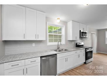 Bright kitchen featuring granite countertops, stainless steel appliances, and white cabinetry at 346 Fieldstone Cir, Statesville, NC 28677