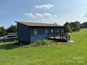 Charming blue home featuring a small deck and a well-manicured lawn in a tranquil setting at 490 County Line Rd, Stony Point, NC 28678