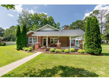 Charming brick home featuring a welcoming front porch, manicured lawn, and mature landscaping at 628 Stamie Dr, Chester, SC 29706