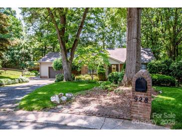 Charming single-story brick home featuring mature trees, lush landscaping, and a welcoming front lawn at 928 Tally Ho Ct, Charlotte, NC 28212