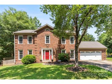 Charming two-story brick home with a manicured lawn, bright red door, and attached two-car garage at 14402 Raynham Dr, Charlotte, NC 28262