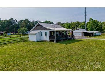 Charming home featuring a large grassy yard and covered porch, complete with a detached garage at 1640 Bear Poplar Rd, Cleveland, NC 27013