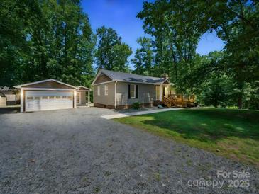 Charming single story home featuring a detached garage, gravel driveway, and a welcoming wooden deck at 2345 Stallings Rd, Matthews, NC 28104