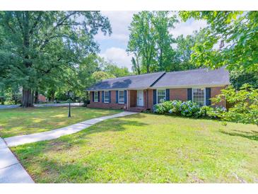 Charming one-story brick home with a well-manicured lawn, blue hydrangeas, and a inviting walkway to the front door at 5720 Amity Pl, Charlotte, NC 28212