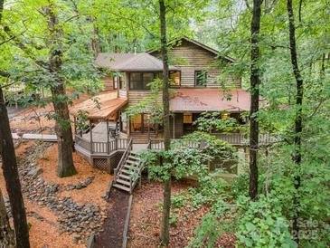 Secluded two-story house featuring mature landscaping, a large deck, and wooden exterior at 676 Cottingham Ne Pl, Concord, NC 28025