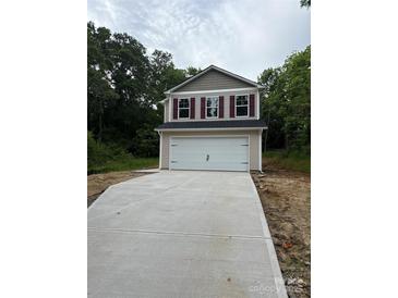Two-story home featuring a large two car garage and concrete driveway surrounded by a lush, wooded landscape at 703 E Dunlap St, Lancaster, SC 29720