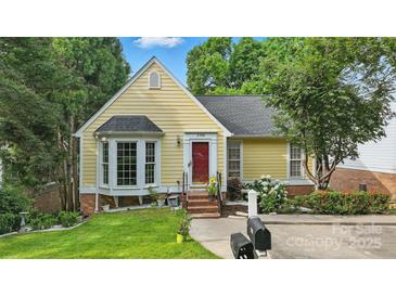 Charming yellow home featuring a red door, bay window, and beautifully landscaped front yard at 2308 Blair House Ct, Charlotte, NC 28270