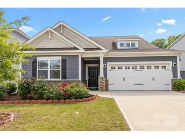 Charming home featuring a two-car garage, stone accents, manicured lawn, and delightful red roses at 4427 Poplin Grove Dr, Indian Trail, NC 28079