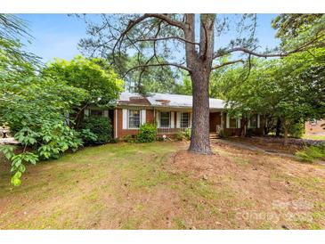 Charming single-story brick home with mature trees and a cozy front porch at 7501 Glencannon Dr, Charlotte, NC 28227