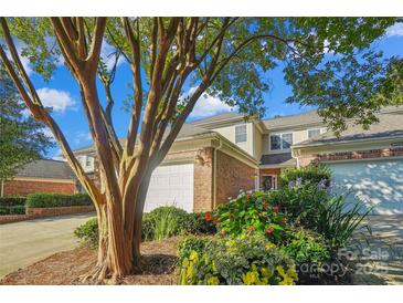 Charming townhouse with brick facade, white garage door, manicured flower garden and mature crape myrtle at 11234 Villa Trace Pl, Charlotte, NC 28277