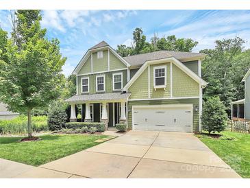 Charming two-story home featuring a manicured lawn, a two-car garage, and classic architectural details at 7011 Hyde Park Dr, Indian Trail, NC 28079