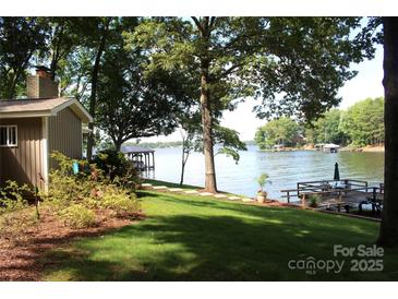 Lakefront backyard with a lush lawn, mature trees and a private dock for enjoying waterfront living at 114 Caraway Ln, Mooresville, NC 28117
