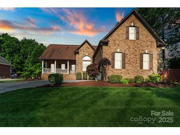 Charming brick home featuring a manicured lawn and mature landscaping, with a picturesque sunset sky at 3831 Riceland Pl, Charlotte, NC 28216