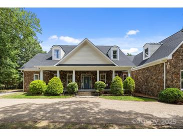 Beautiful stone house featuring a manicured lawn, dormer windows, and a charming front porch with stone columns at 9261 Marvin School Rd, Marvin, NC 28173