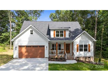 Charming two-story home with white siding, dark roof, inviting front porch, and a well-maintained, attached brown garage at 1004 E Sandy Ridge Rd, Monroe, NC 28112