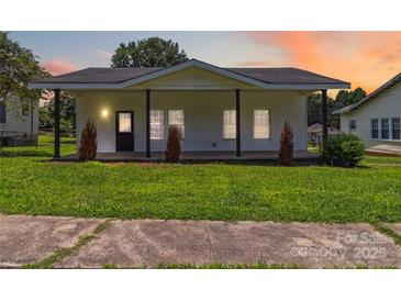 Charming white home with a welcoming porch and well-manicured lawn, ideal for Gathering living at 113 Woodside Ave, Gastonia, NC 28054