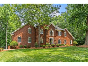 Charming red brick home with lush green lawn and mature trees offering curb appeal and natural beauty at 1310 Weddington Hills Dr, Matthews, NC 28104