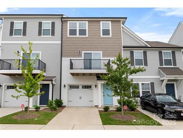 Charming townhome featuring a balcony, attached garage, and manicured lawn, showcasing a modern design at 15034 Scoter St, Charlotte, NC 28262