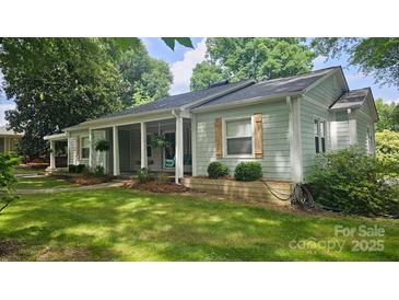 Charming home with light green siding, wooden shutters, and a covered front porch with hanging plants at 415 S Central Ave, Locust, NC 28097