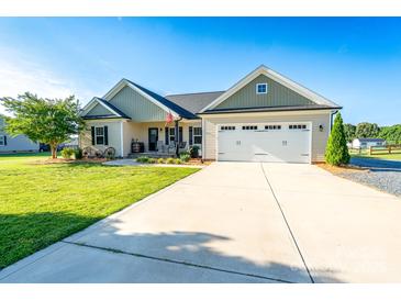 Charming single-story home with a manicured lawn, a two-car garage, and a welcoming front porch at 17438 Purser Dr, Locust, NC 28097