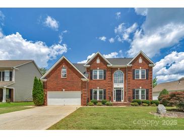 Charming two-story brick home with a well-manicured lawn and beautiful landscaping under a cloudy sky at 7800 Conifer Cir, Indian Trail, NC 28079