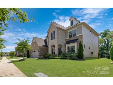 Beautiful two-story home featuring stone accents, arched entryway, manicured lawn, and three car garage at 11313 Limehurst Pl, Charlotte, NC 28278