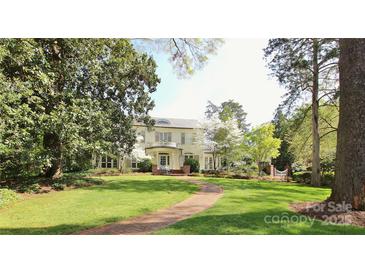 Charming two-story home with a brick walkway, lush green lawn, and mature trees offering shade at 1137 Queens W Rd, Charlotte, NC 28207