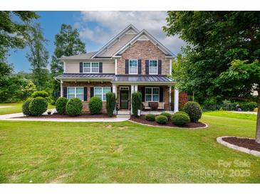 Charming two-story home featuring a manicured lawn and inviting front porch with stone and siding accents at 2405 Emma Grace Ln, Rock Hill, SC 29732