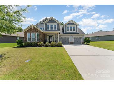 Charming two-story home with stone accents, a well-manicured lawn, and a three-car garage at 2606 Cheverny Pl, Concord, NC 28027