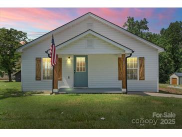 Charming single-story home with a well-manicured lawn, front porch, American flag, and rustic wooden shutters at 321 E Taylor St, Landis, NC 28088