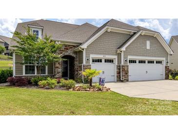 Charming home exterior boasts a well-manicured lawn, stone accents, and a two-car garage at 8035 Pastime Ln, Clover, SC 29710