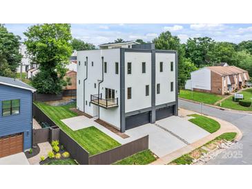 Modern, three-story home featuring a balcony, well-manicured lawn, and a two-car garage at 129 French St, Charlotte, NC 28216