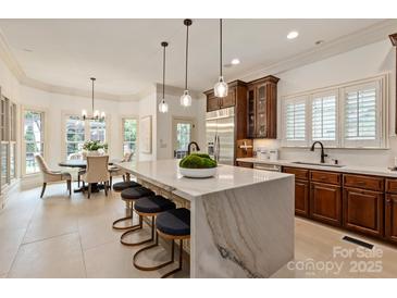 Elegant kitchen features a marble waterfall island with seating and stainless steel appliances at 1500 Lookout Cir, Waxhaw, NC 28173
