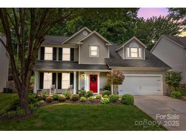 Charming two-story home with a red door, landscaped yard, and inviting front porch at 8700 Fox Tail Ln, Huntersville, NC 28078