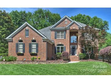 Stunning brick home featuring lush landscaping, a manicured lawn, and charming architectural details at 12644 Lahinch Ct, Charlotte, NC 28277