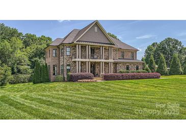 Stunning stone home with a manicured lawn and covered front porch with columns, showcasing elegance at 14041 Mccord Rd, Huntersville, NC 28078