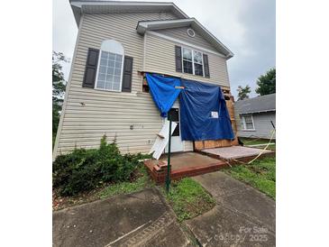 Damaged two-story home featuring a front porch, siding, and windows covered with a blue tarp at 2012 Ashley Rd, Charlotte, NC 28208