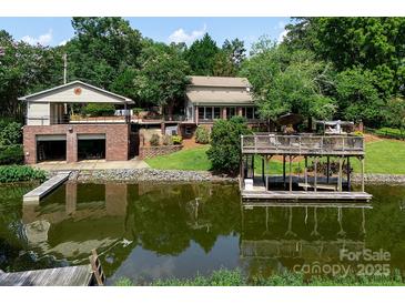 Beautiful waterfront home featuring a dock and multi-car garage, surrounded by lush landscaping and serene water views at 24756 Strand Dr, Albemarle, NC 28001