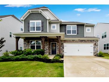 Charming two-story home featuring a stone facade, two-car garage, and well-manicured lawn at 334 Kennerly Center Dr, Mooresville, NC 28115